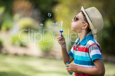 Young boy in sunglasses blowing bubbles through bubble wand