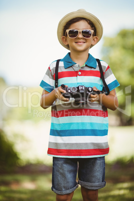 Young boy in sunglasses holding a camera