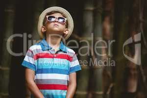 Young boy in sunglasses standing in forest