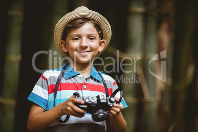 Smiling young boy in hat holding a camera