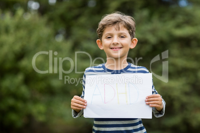 Boy in park holding placard that reads alphabets