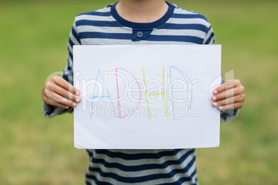 Boy in park holding placard that reads alphabets