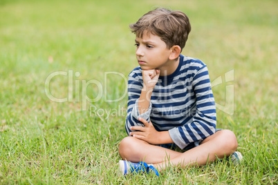 Upset boy sitting on grass