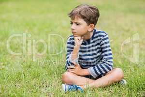 Upset boy sitting on grass