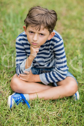 Upset boy sitting on grass