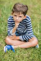 Upset boy sitting on grass