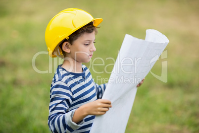 Boy in hard hat reading a plan