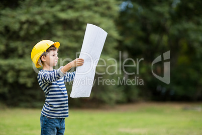 Boy in hard hat reading a plan
