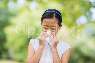 Girl blowing her nose with handkerchief while sneezing