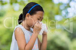 Girl blowing her nose with handkerchief while sneezing