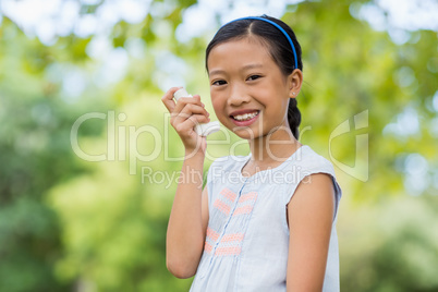 Portrait of girl using an asthma inhaler in the park