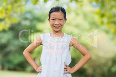 Portrait of smiling girl standing with hand on hip