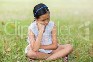 Upset girl sitting on grass