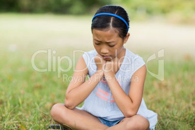 Upset girl sitting on grass