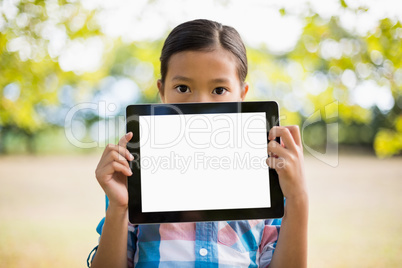 Portrait of girl showing digital tablet in park