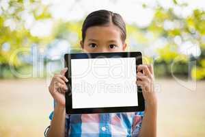 Portrait of girl showing digital tablet in park