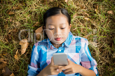 Girl lying on grass and using mobile phone