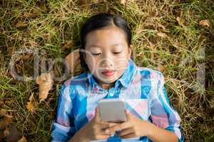 Girl lying on grass and using mobile phone