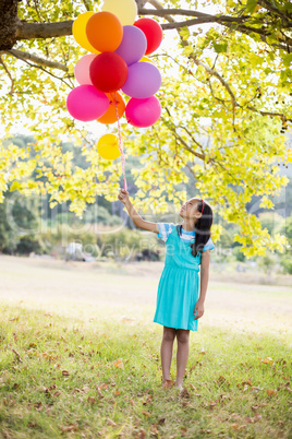 Smiling girl holding balloons in the park