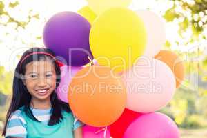 Portrait of smiling girl holding balloons in park