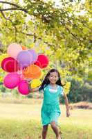 Portrait of smiling girl playing with balloons in the park