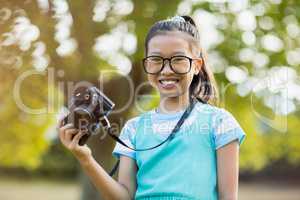 Portrait of smiling girl in spectacle holding a camera