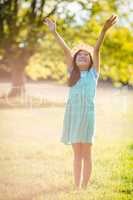 Smiling girl standing with arms outstretched in park