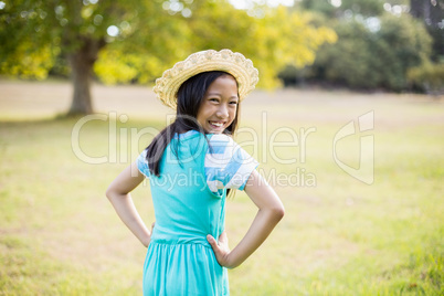 Portrait of smiling girl standing with hand on hip in park