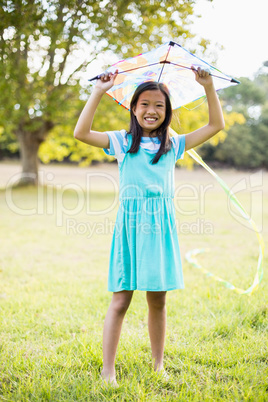 Portrait of smiling girl holding kite in park