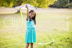 Portrait of smiling girl holding kite in park