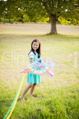 Portrait of smiling girl playing with kite in park