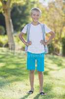 Portrait of smiling boy standing with hand on hip in park