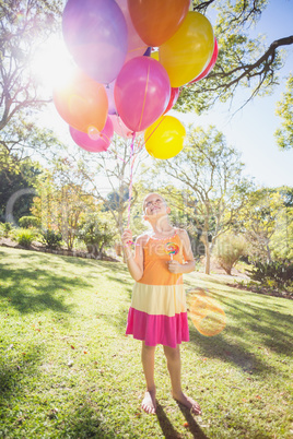 Smiling girl holding with balloons in the park