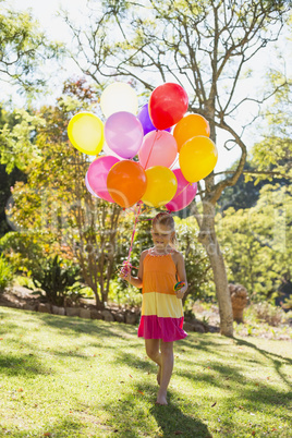 Girl walking with lollipop and balloons in park