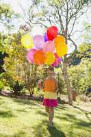 Girl walking with lollipop and balloons in park