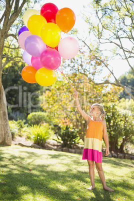 Smiling girl holding with balloons in the park