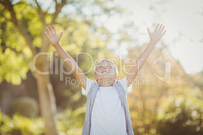 Boy standing with arms outstretched in park