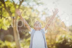 Boy standing with arms outstretched in park