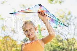 Portrait of smiling girl holding kite in park