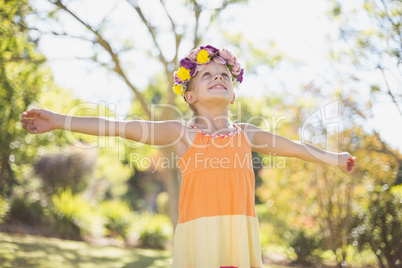 Girl wearing wreath standing with arms outstretched in park