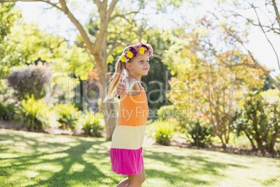 Girl wearing wreath standing with arms outstretched in park