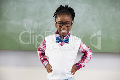 Portrait of happy schoolgirl standing with hand on hip