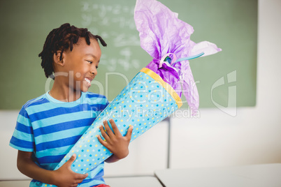 Happy schoolboy holding gift in classroom