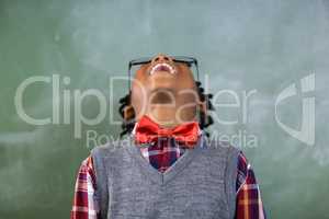 Happy schoolboy looking up and laughing in classroom