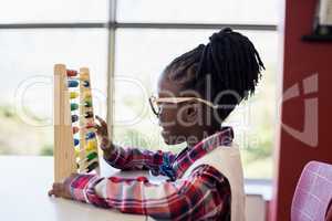 Schoolgirl using a maths abacus in classroom