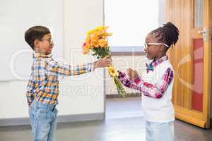 Schoolboy giving a bunch of flowers to a girl
