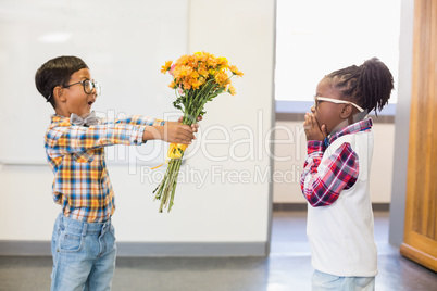 Schoolboy giving a bunch of flowers to a girl