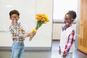 Schoolboy giving a bunch of flowers to a schoolgirl