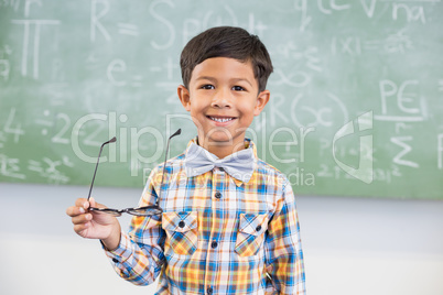 Portrait of schoolboy smiling against chalkboard in classroom