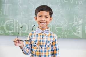 Portrait of schoolboy smiling against chalkboard in classroom